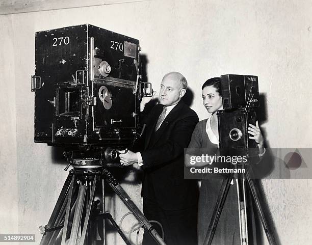 Cecil B. DeMille and his script girl, Emily Barrye, who has been with the director half of his twenty years in motion pictures, compares a modern...