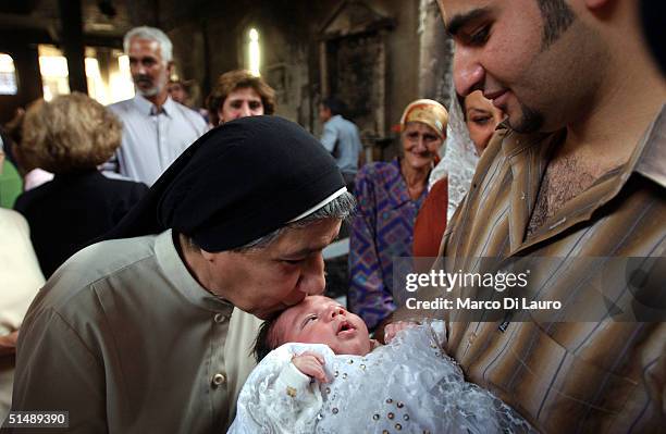 An Iraqi nun kisses a baby after being baptized during Sunday services at a destroyed Roman Catholic Church October 17, 2004 in Baghdad, Iraq. On...