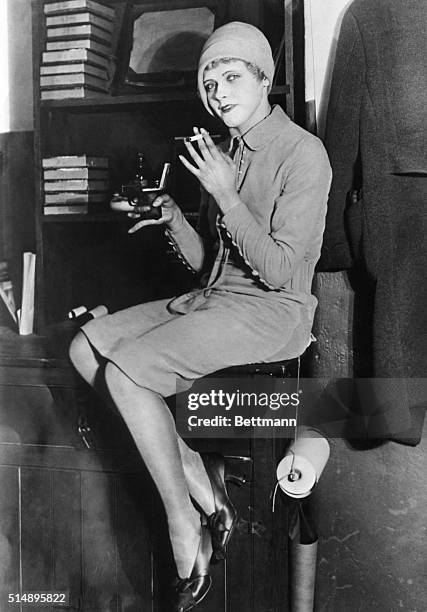 Flapper sitting on a desk smoking. Undated photograph, ca. 1920's.