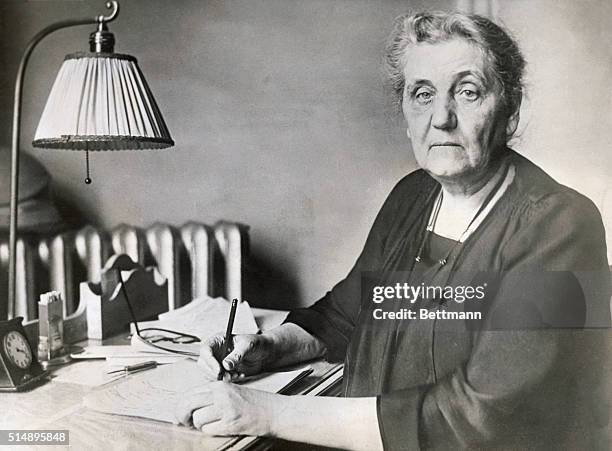 Jane Addams , internationally known social worker and author, writes at her desk. Miss Addams established the social settlement, Hull House, in...