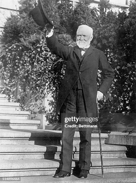 New York, New York: Picture shows industrialist Andrew Carnegie standing on the steps of his estate wearing a suit and waving his hat. Undated photo...