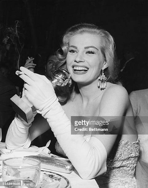 Candid Hollywood...Anita Ekberg, named the International Star of Tomorrow by the Hollywood Foreign Press, clutches her trophy and radiantly smiles...