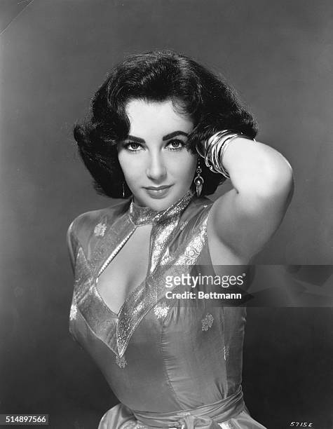 Actress Elizabeth Taylor is shown in a seductive pose, left hand behind her head. Ca. 1950s-60s.