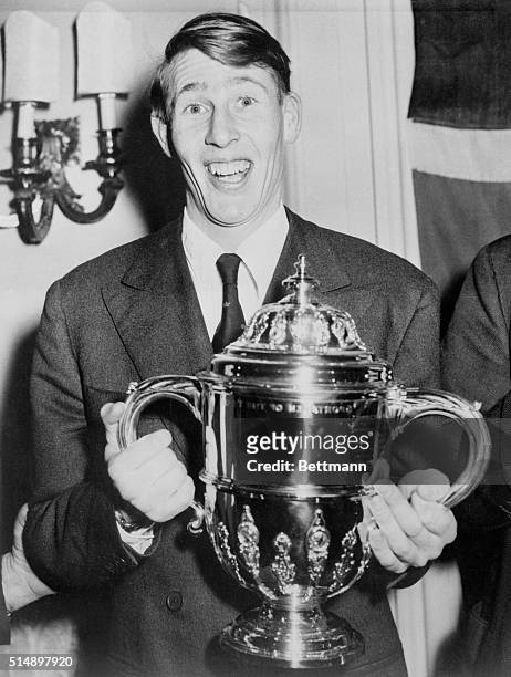 Roger Bannister, first man to run a mile in less than four minutes, holds the Sporting Record Trophy, which was presented to him in London at...