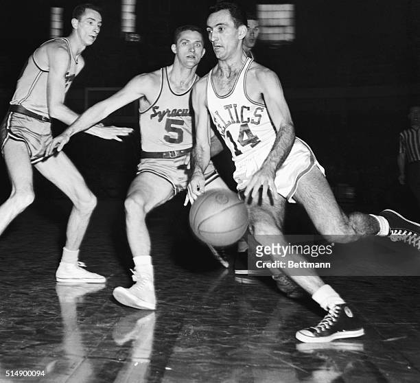 Bob Cousy of the Boston Celtics moves into score through Syracuse Men, Red Rocha and Paul Seymour , in the second quarter of the playoffs game at the...