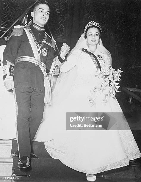 Photo shows Hussein Ibn Talal, King of Jordan holding the hand of his first bride, Princess Dina, daughter of Prince Abdel-Hamin Aoun of Hijaz,...