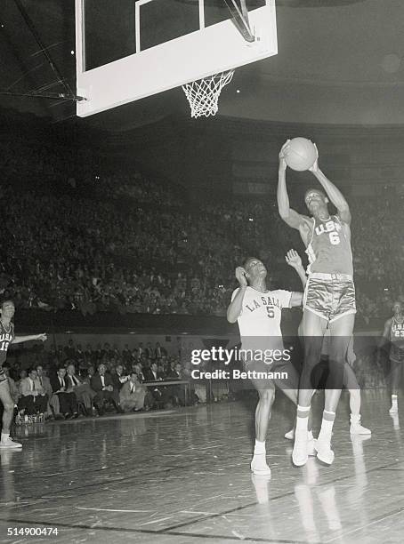 Kansas City, MO.: Bill Russell, 6-foot-9 inches, University of San Francisco center, dwarfs LaSalle's Alonzo Lewis as he snatched a high pass during...