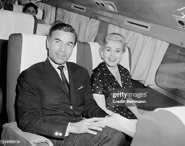 Dominican diplomat Porfirio Rubirosa and lovely actress Zsa Zsa Gabor smile as they pass through Miami en route to the West Coast. The actress said...