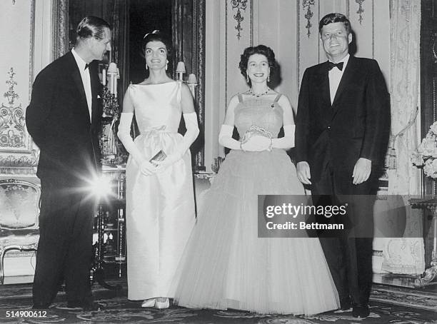 Royal Dinner for Kennedys. London: Prince Philip chats with Mrs. Jacqueline Kennedy while the President and Queen Elizabeth watch the photographer...