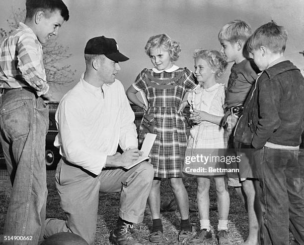 Mickey Mantle is shown here signing autograph books for some of the neighbor's kids on Commerce Oklahoma High School football field.