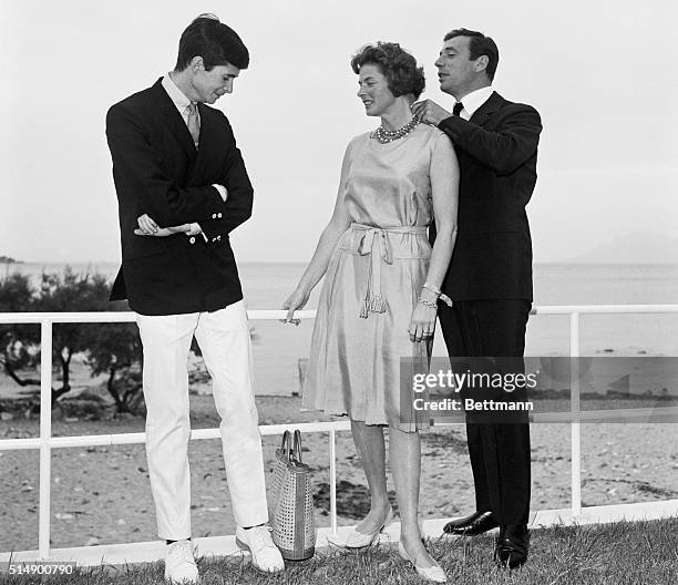 International Stars. Canes, France: Anthony Perkins watches as Yves Montand adjusts a necklace on Ingrid Bergman after a luncheon attended by the...