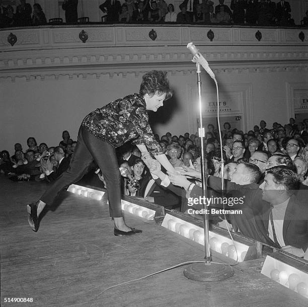 Judy Garland leans over the footlights to greet some of her enthusiastic fans during her concert at Carnegie Hall. Judy thrilled a standing-room-only...