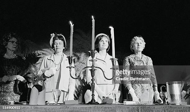 Mrs. John F. Kennedy is framed thru a candelabrum as she joins in prayer at a Congressional's Women's luncheon at the Sheraton park Hotel here today....