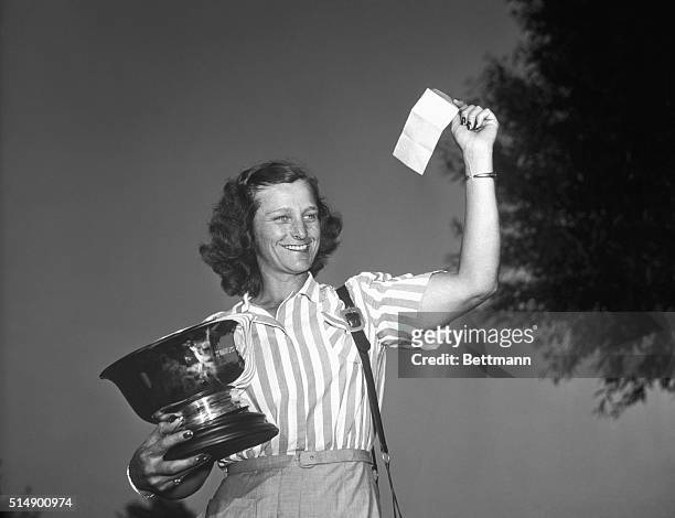 Babe Zaharias holding Women's National Open Golf Tourney trophy and waving check representing first prize of $1,200.00.