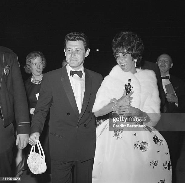 Santa Monica, California: Elizabeth Taylor and Eddie Fisher leave the theater after Academy Awards presentations. Liz proudly walks with "Oscar."