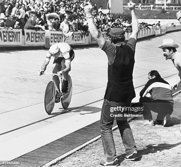 Francesco Moser's mechanic throws up his hands and cheers as Moser speeds by setting a record for 20 kilometers at Mexico City's Olympic Velodrome....