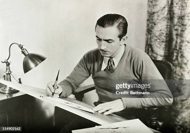 Walt Disney , famed orignator of full-length animated motion pictures, at work at his drawing board.