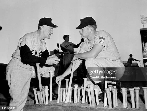 Yankee manager Casey Stengel seems to be giving Mickey Mantle some advice as they confer over the bat rack at Cleveland Municipal Stadium before the...