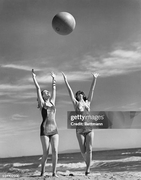 Hollywood, California: Mary Howard and Ann Morris are shown playing ith a ball on the beach. One woman is wearing a solid bathing suit, the other a...