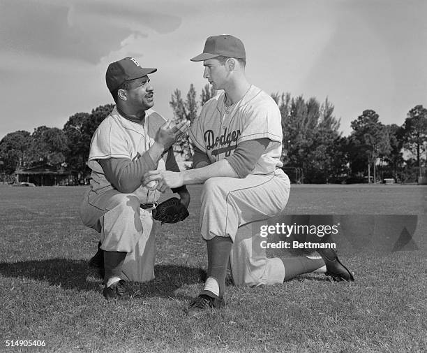 Photo shows catcher Roy Campanella giving advice to young bonus player from Brooklyn who pitched two shut-outs last year, Sandy Koufax.