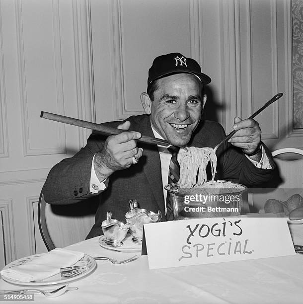 Yogi Berra playfully digs into a pot of spaghetti for photographers during a press luncheon where he was named the Yankees' new manager. The former...