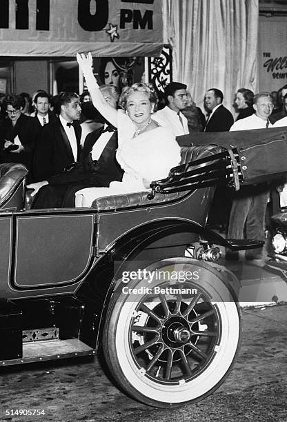 Mary Pickford, in the back of a vintage 1912 Buick, waves to the crowd as she arrives for a benefit premiere in Hollywood.