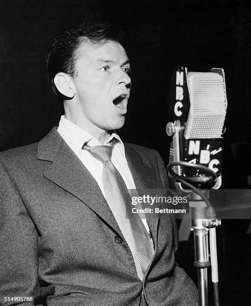 Waist-up portrait of singer/actor Frank Sinatra singing into an NBC microphone. Undated photograph.
