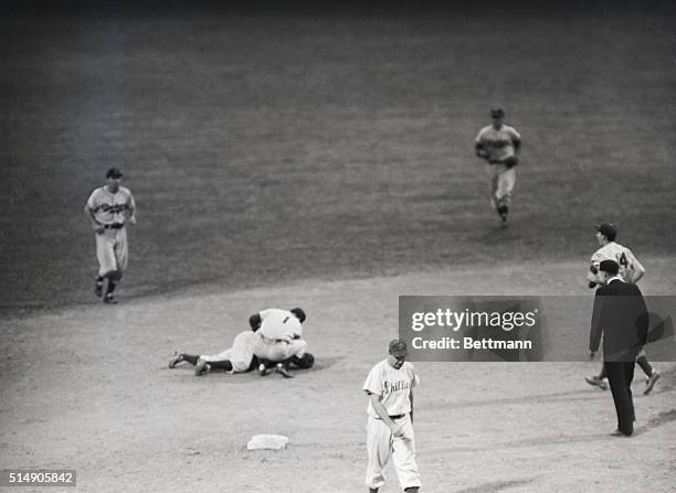 Jackie Robinson of the Brooklyn lies on the ground with teammate Reese bending over him after catching a line drive hit by Waitkus of the Phil...