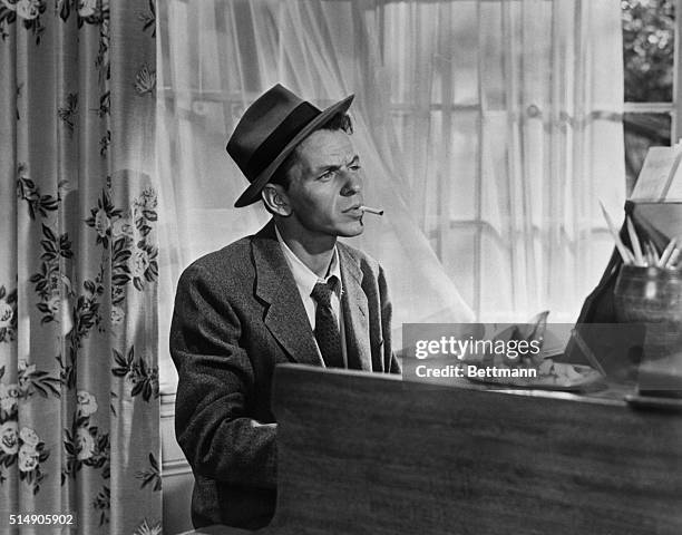 In a classic pose, Frank Sinatra smokes a cigarette as he plays piano in the movie Young at Heart. One of the movie's songs became a trademark...