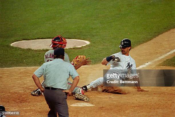 New York, NY: Don Mattingly is safe sliding into home plate, beating the tag of Cleveland Indians catcher Sandy Alomar Jr., scoring the winning run...