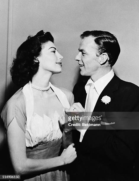 Displaying their wedding bands, film actress Ava Gardner and crooner Frank Sinatra gaze at each other following their wedding at the home of a...