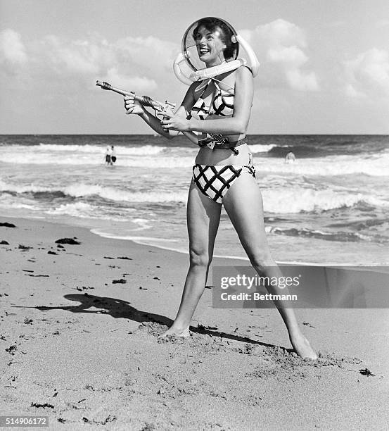 Model Bunny Yeager, pointing a "ray gun," wears a space helmet with her bikini on Miami Beach.