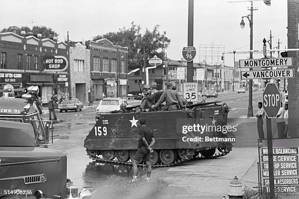 Detroit, MI: A Michigan National Guard armored personnel carrier stands guard along with five tanks and a small fleet of helicopters in an attempt to...