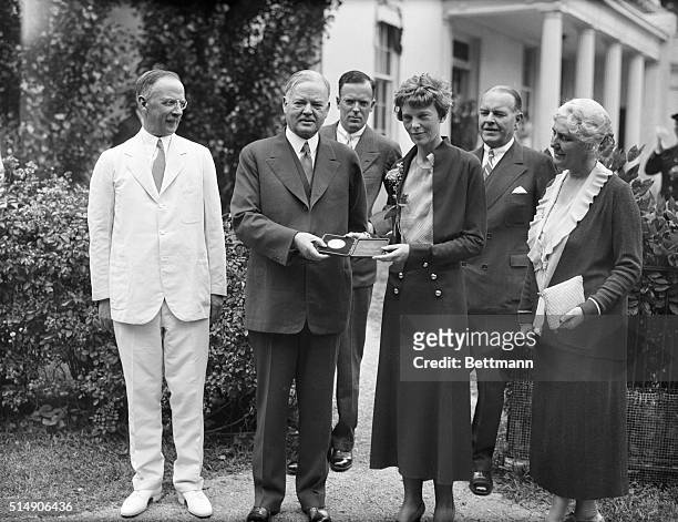 President Herbert Hoover presenting the National Geographic Society gold medal to Amelia Earhart in recognition of her continuous solo flight across...