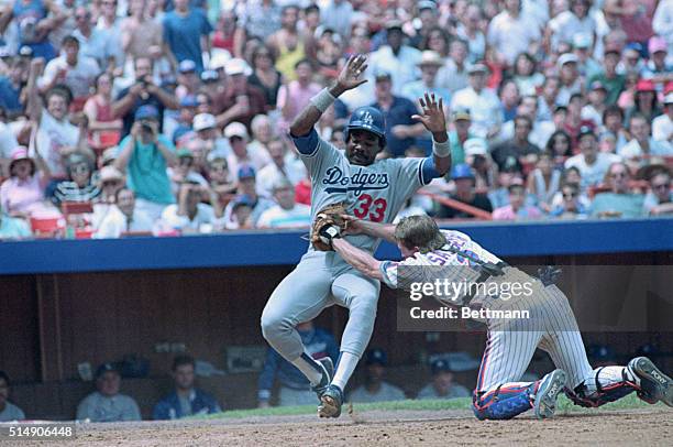New York, NY: Dodgers' Eddie Murray is tagged out bu Mets catcher Mackey Sasser as he slides into home plate in the fourth inning at Shea Stadium...