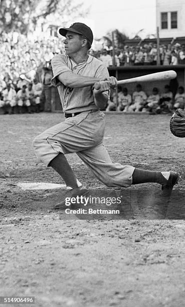 Miami, FL- Pee Wee Reese, back at his post in the Brooklyn Dodgers' infield, takes a hard cut at the ball in the fifth inning of a pre-season game...