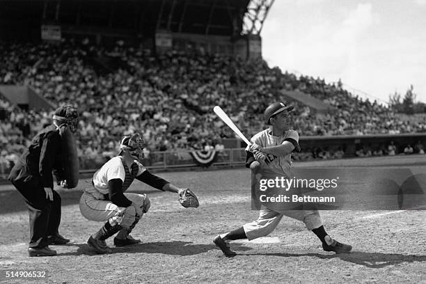 Miami, FL: Miami Stadium. Yogi Berra of the Yankees is shown driving a long one for a homerun during an exhibition game against the Baltimore Orioles.
