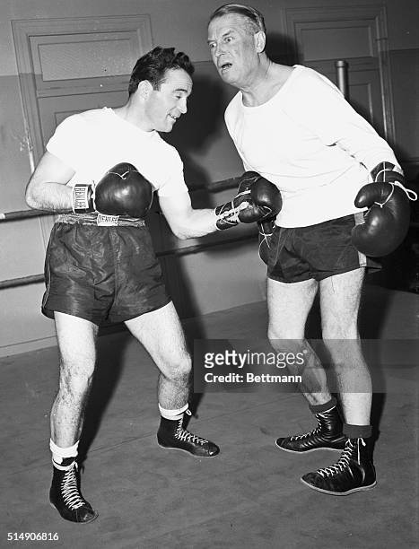 New York- Maurice Chevalier, noted French comedian and singer, gives out with a French-American "oof" as countryman Marcel Cerdan, European...