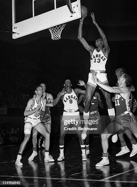 Kansas City, MO- Up, up, goes giant Wilt "The Stilt" Chamberlain , of Kansas, to score easily over heads of San Francisco Dons during semi-final game...