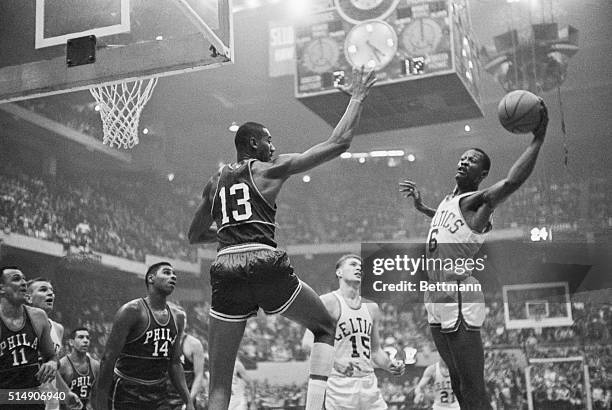 Wilt Chamberlain goes up to block Bill Russell's shot during action at Boston Garden as Tom Heinsohn & Woody Sauldsberry look on.