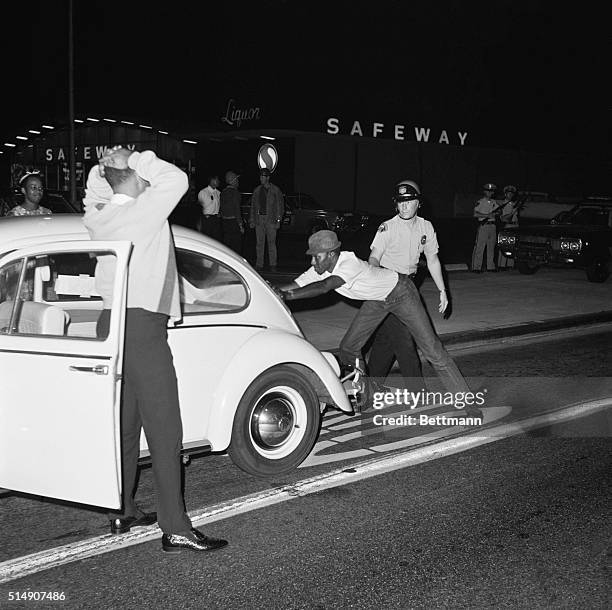 Long Beach police officer searches Black drivers and passengers for weapons at a checkpoint, during the Watts Riots in nearby Los Angeles.