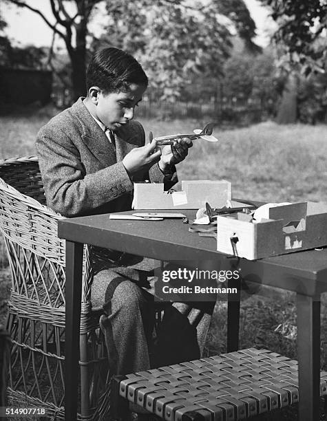 Young King Faisal II enjoys playing with model aircraft. Here he is preparing one of the models for flight. The royal scholar is busily assembling...