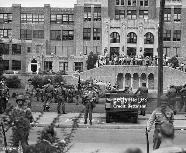 Federal troops stand guard as African American students join White students in front of Central High School after Federal courts ordered the...