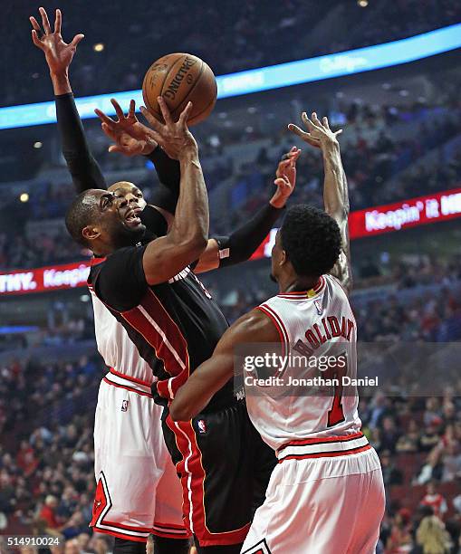 Dwyane Wade of the Miami Heat puts up a shot between Taj Gibson and Justin Holiday of the Chicago Bulls at the United Center on March 11, 2016 in...