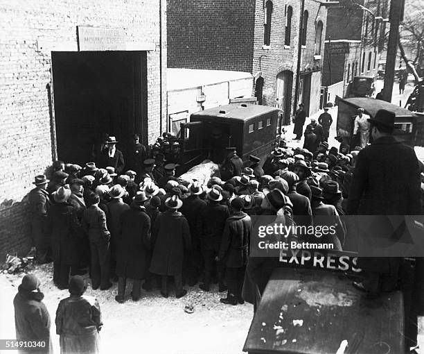 Onlookers watch as police remove the bodies of the victims of an execution style murder from the scene at 2122 North Clark Street in Chicago. The...