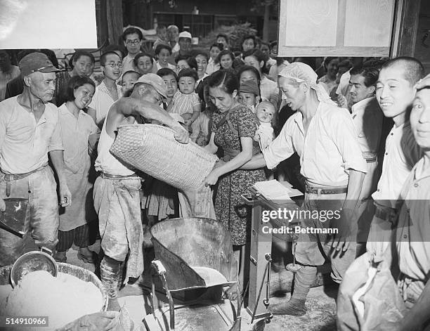 Tokyo, Japan-A workman is shown handing out individual rations of the largest single amount of U.S. Food ever released in Japan 250 tons of wheat...