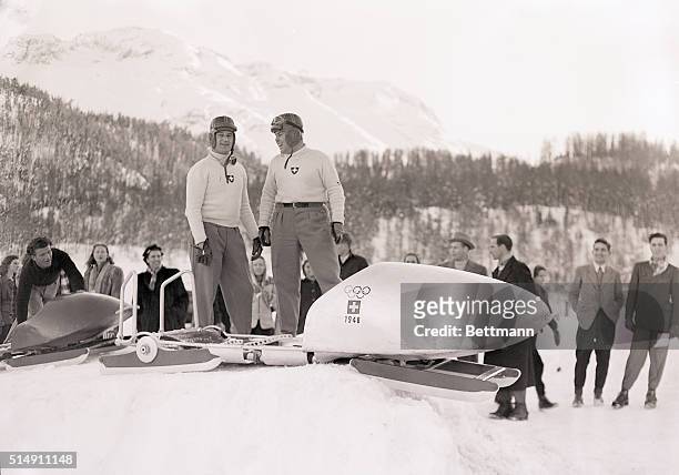 St,Moritz, Switzerland- These two dare-devils, members of the Swiss Olympic squad, relax by their bobsled after winning the two-man bobsled event....