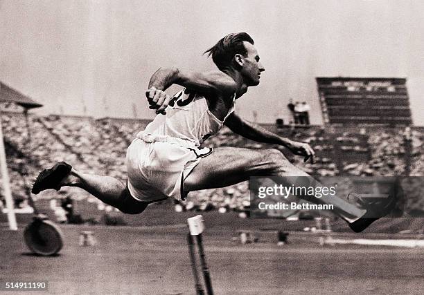 Wembley, England- Roy Cochran goes over a hurdle in trial heat on July 29. Cochran went on to cop the 400-meter hurdle event at the Olympics in new...