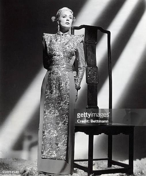 Hollywood, CA- The style of this dramatic dinner gown, worn by Jane Havoc in, "Intrigue", was borowed from the Mandarins. Rich Chinese brocade is...