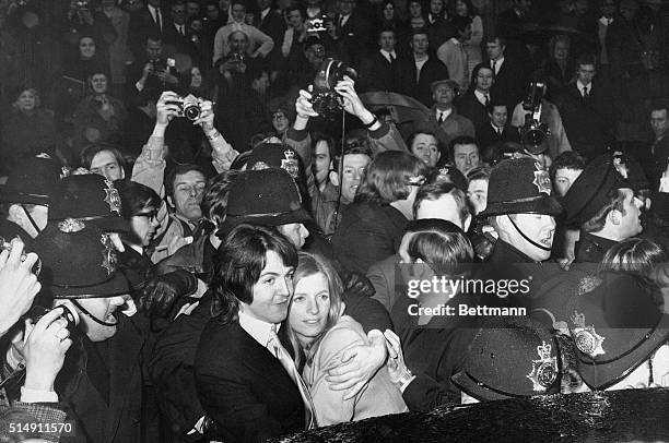 Police officers surround Paul McCartney and new wife Linda McCartney as they make their way through fans following their marriage in London.